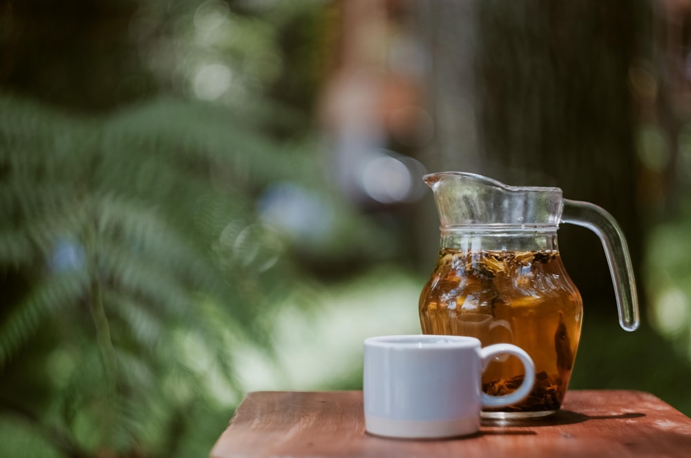 full glass of clear glass pitcher beside white ceramic teacup