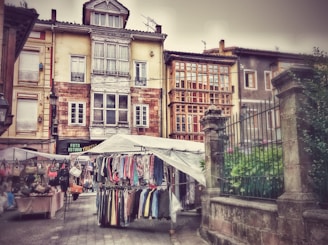 Vintage market stalls lined with antique treasures and vibrant fabrics in a quaint village square.