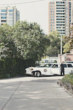 Chauffeur in crisp uniform standing ready beside a Cadillac Escalade under soft evening lighting.