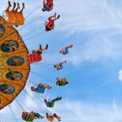 people riding carnival ride under blue skies