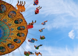 people riding carnival ride under blue skies