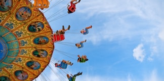 people riding carnival ride under blue skies