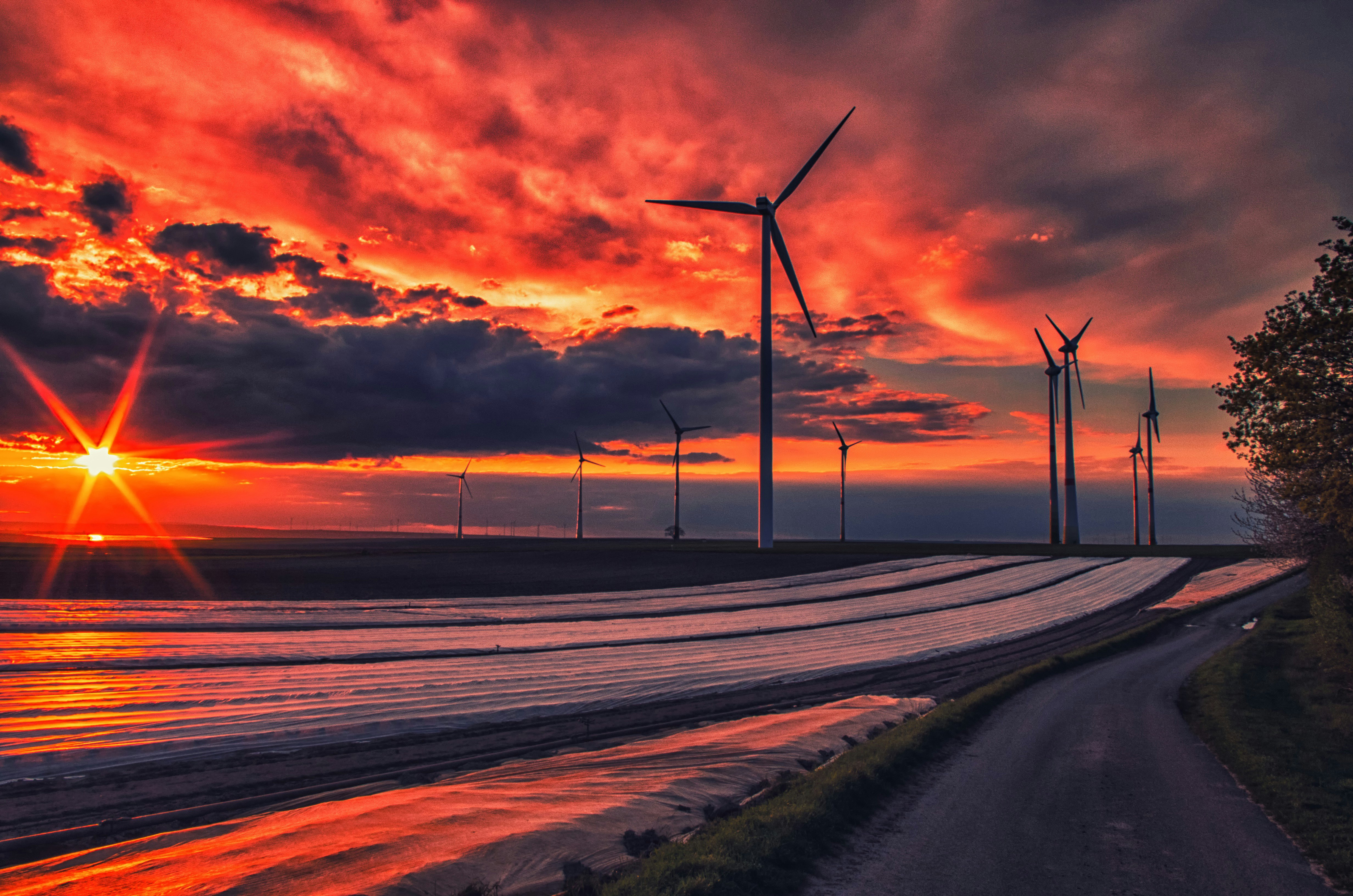 wind turbines on gray asphalt road during sunset