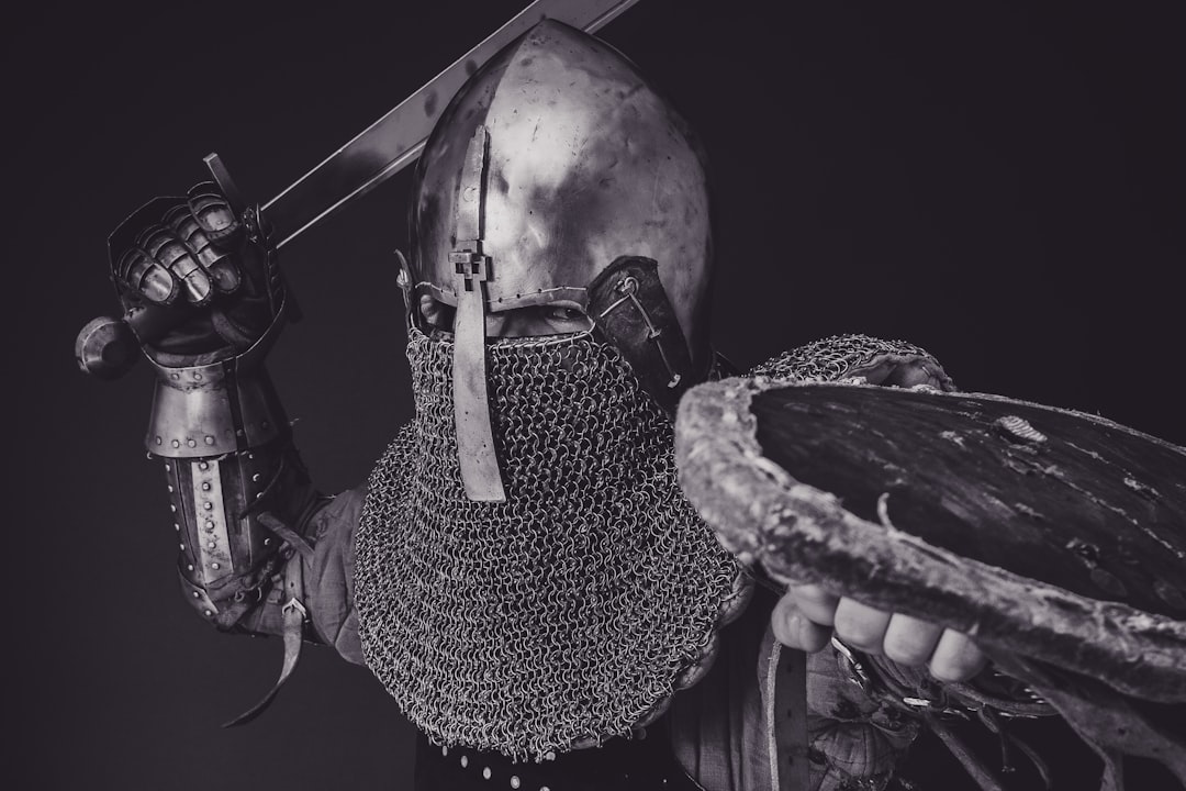 black and white portrait of a man in Medieval armor, getting ready to swing a sword.