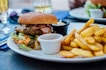 selective focus photography of burger patty, mayonnaise, and French fries served on platter
