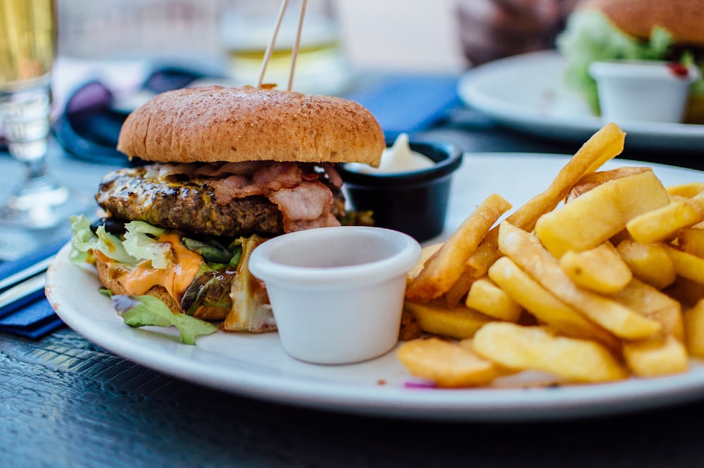 fotografia de foco seletivo de hambúrguer, maionese e batatas fritas servidas na travessa