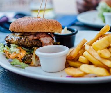 selective focus photography of burger patty, mayonnaise, and French fries served on platter