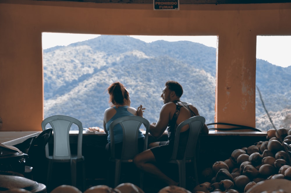 um homem e uma mulher sentados em uma mesa em frente a uma janela