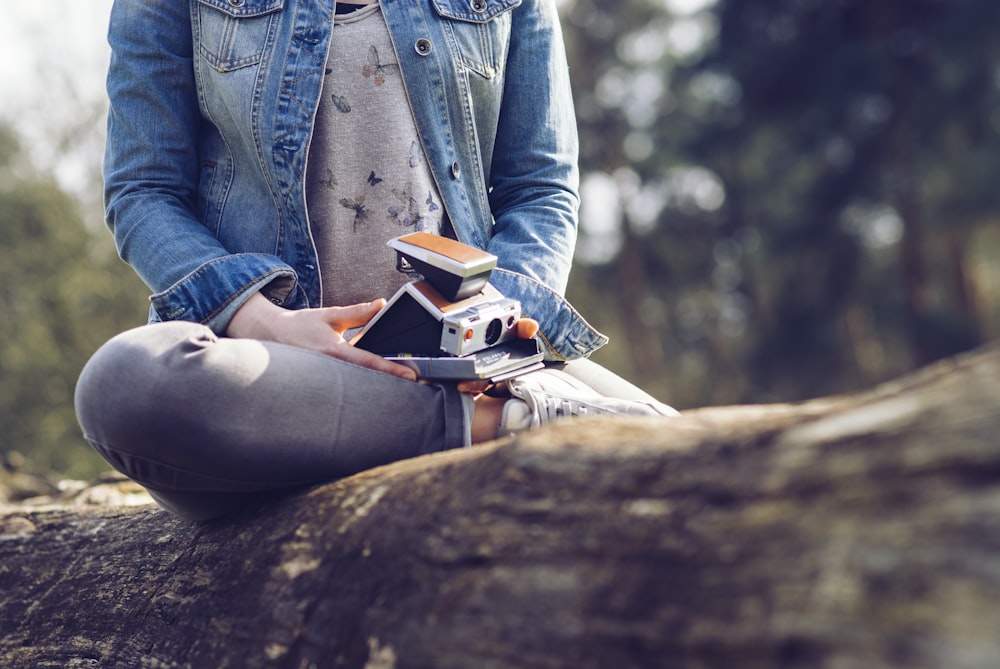 Femme assise sur un journal tenant un appareil photo et un livre