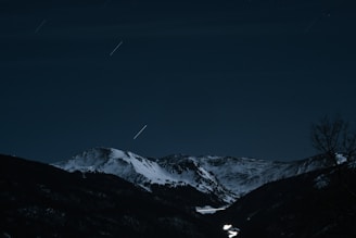 the night sky over a snowy mountain range