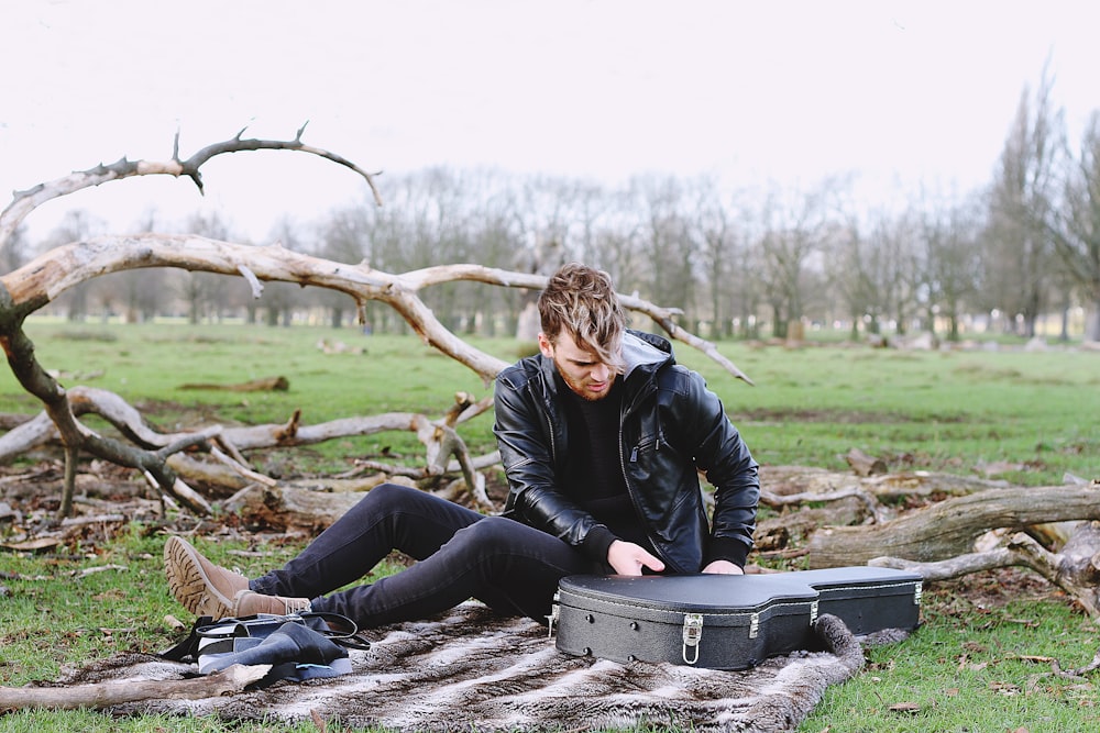 man siting holding guitar case