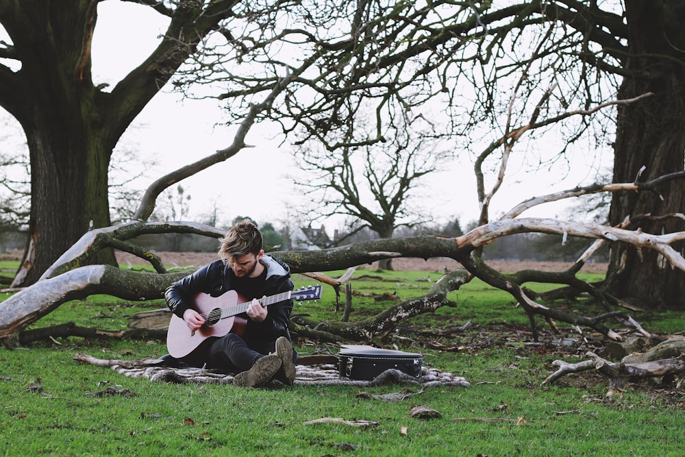 uomini che tengono una chitarra vicino agli alberi durante il giorno