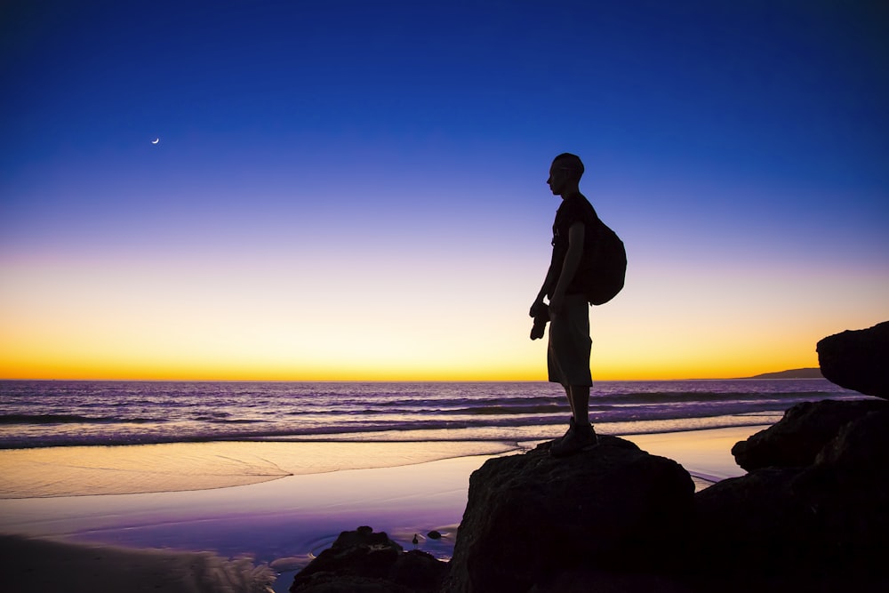 silhouette of man standing on cliff