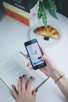 person using phone in front of open book