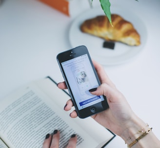 person using phone in front of open book