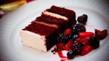 Delicious chocolate cake slice topped with fresh berries on a white plate.