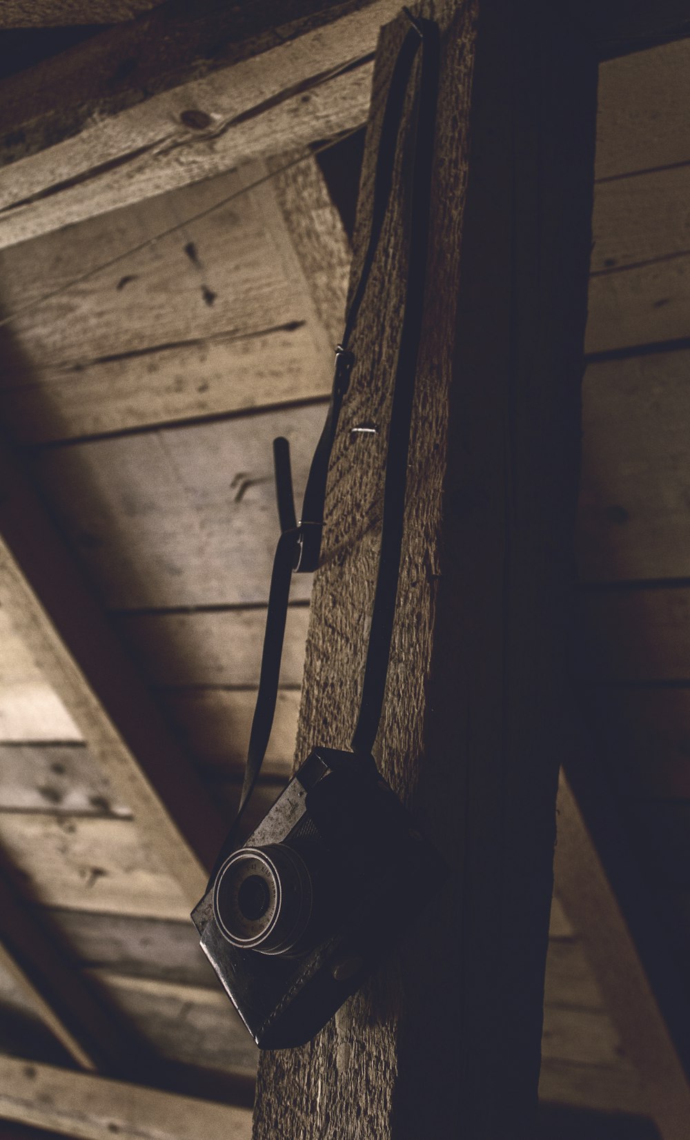 Fotocamera nera point-and-shoot appesa a una barra di legno marrone