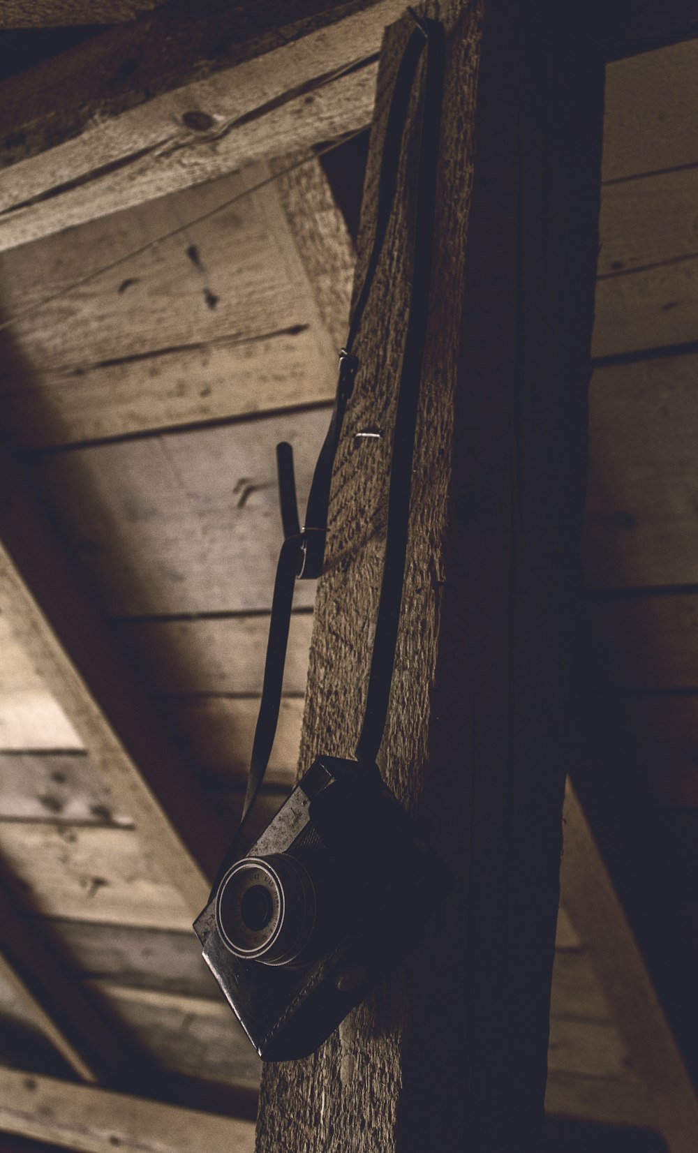 black point-and-shoot camera hanging on a brown wooden bar