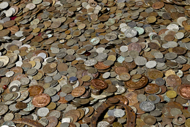 An assortment of gold and silver coins spread out on a rustic table, showcasing variety.