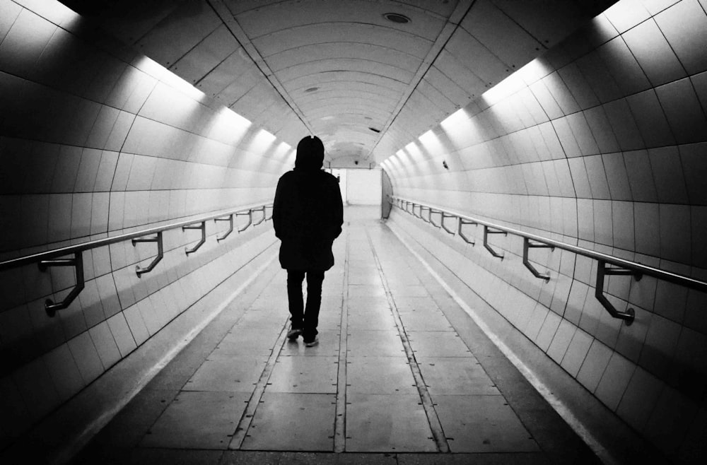 Frau im schwarzen Mantel geht durch den Tunnel