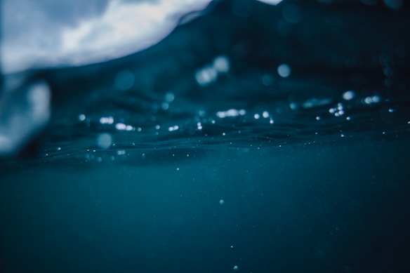 Deep underwater scene capturing the texture and movement of water, with bubbles and a play of light creating an ethereal atmosphere.