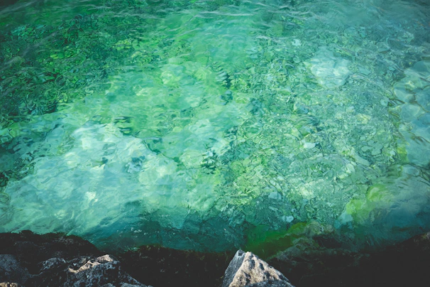 Crystal-clear turquoise waters with a snorkeler admiring colorful marine life near a rocky shore.