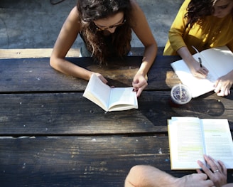 woman reading book while sitting on chair