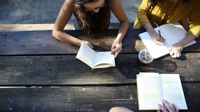 woman reading book while sitting on chair