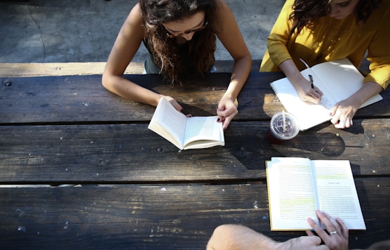 woman reading book while sitting on chair