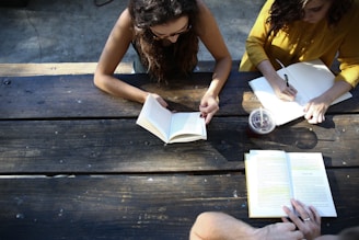 woman reading book while sitting on chair