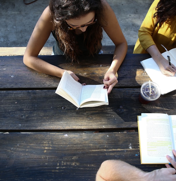 woman reading book while sitting on chair