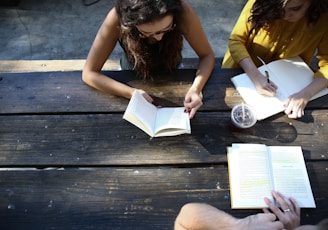 woman reading book while sitting on chair