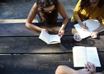 woman reading book while sitting on chair