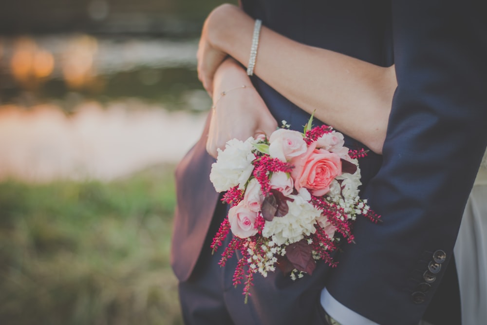 男性を抱きしめながら花束を持つ女性