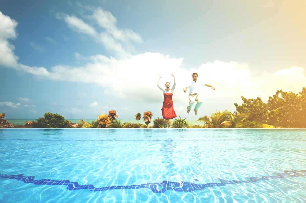 man and woman jumping onto pool
