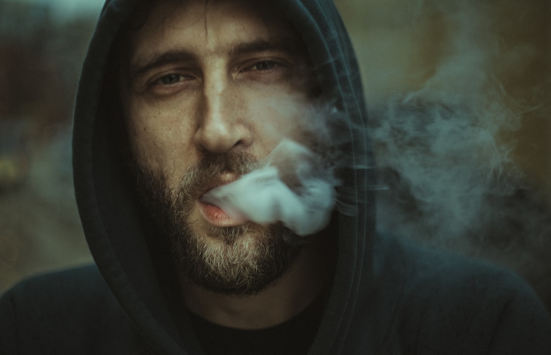 man wearing black pullover hoodie blowing white smoke