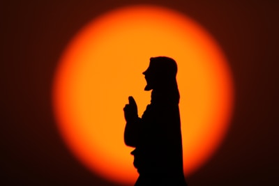 A determined man praying with a sunrise in the background symbolizing new beginnings.