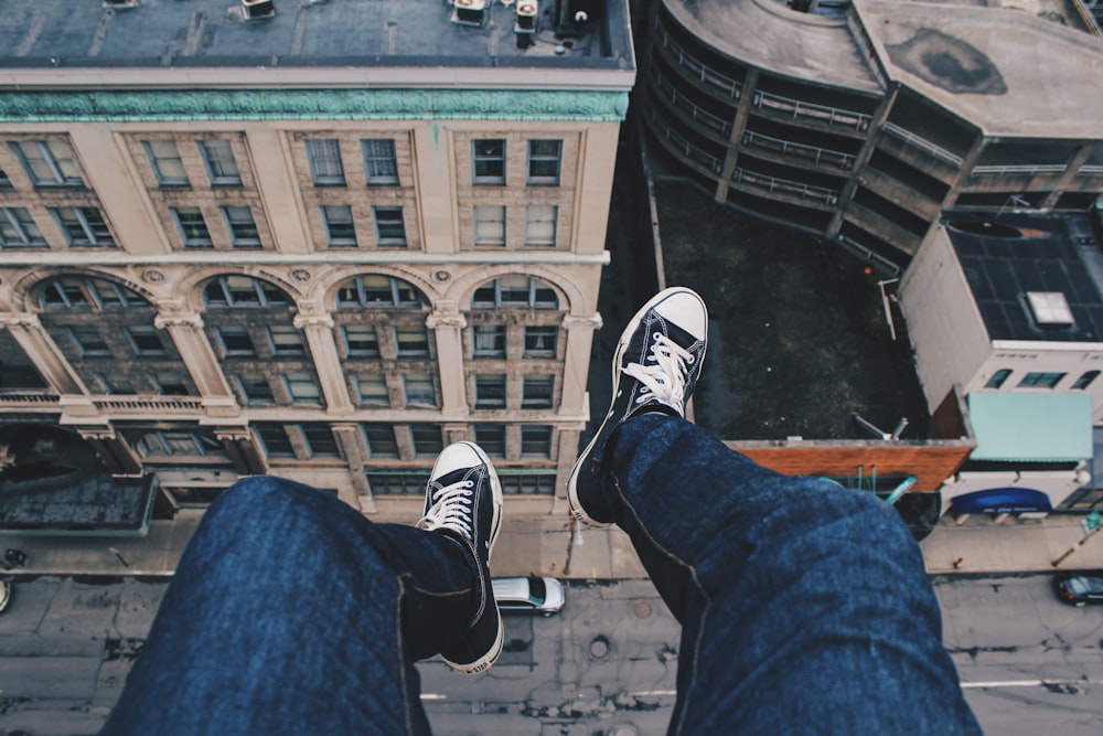 person sitting on cliff above building