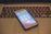 A smartphone displaying a call screen rests on the keyboard of a laptop. The laptop keyboard is slightly out of focus, and the smartphone shows an ongoing call with several icons for call options.