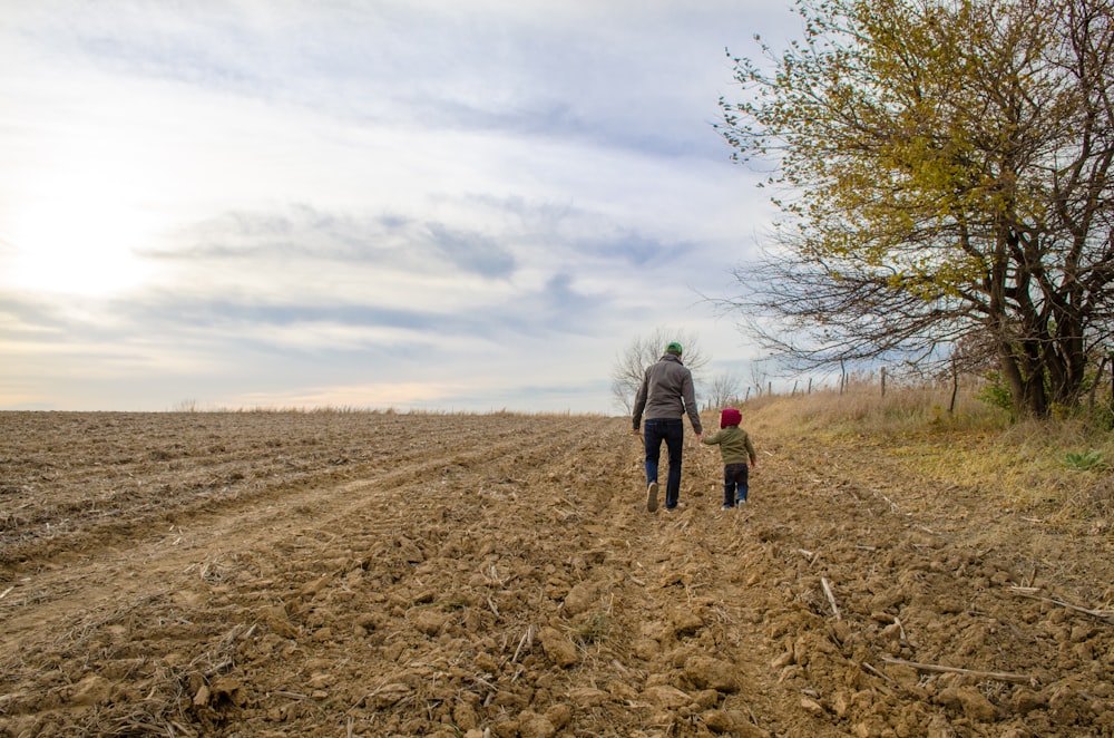 Un père marchant avec son enfant dans un champ.