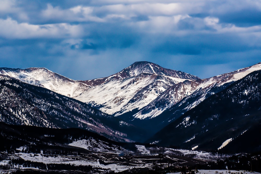 snow-covered mountain under clouded sky