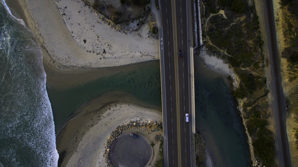 aerial photography of black and white vehicles on road between body of water and