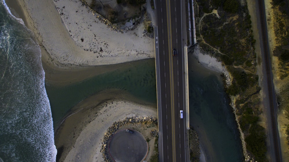 Fotografía aérea de vehículos en blanco y negro en la carretera entre el cuerpo de agua y