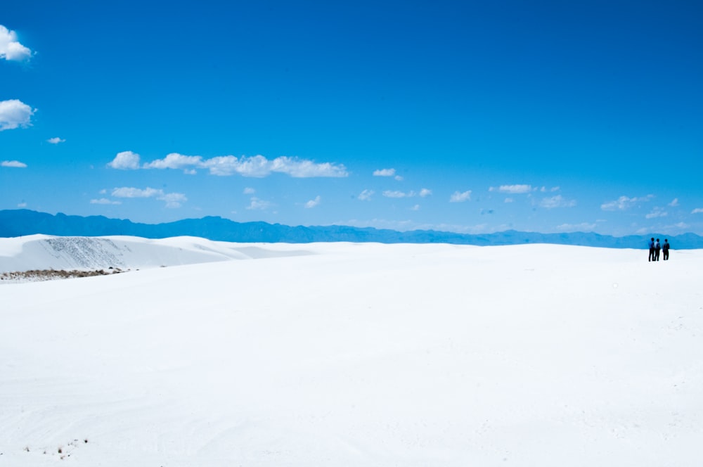 tres personas de pie en un campo de nieve