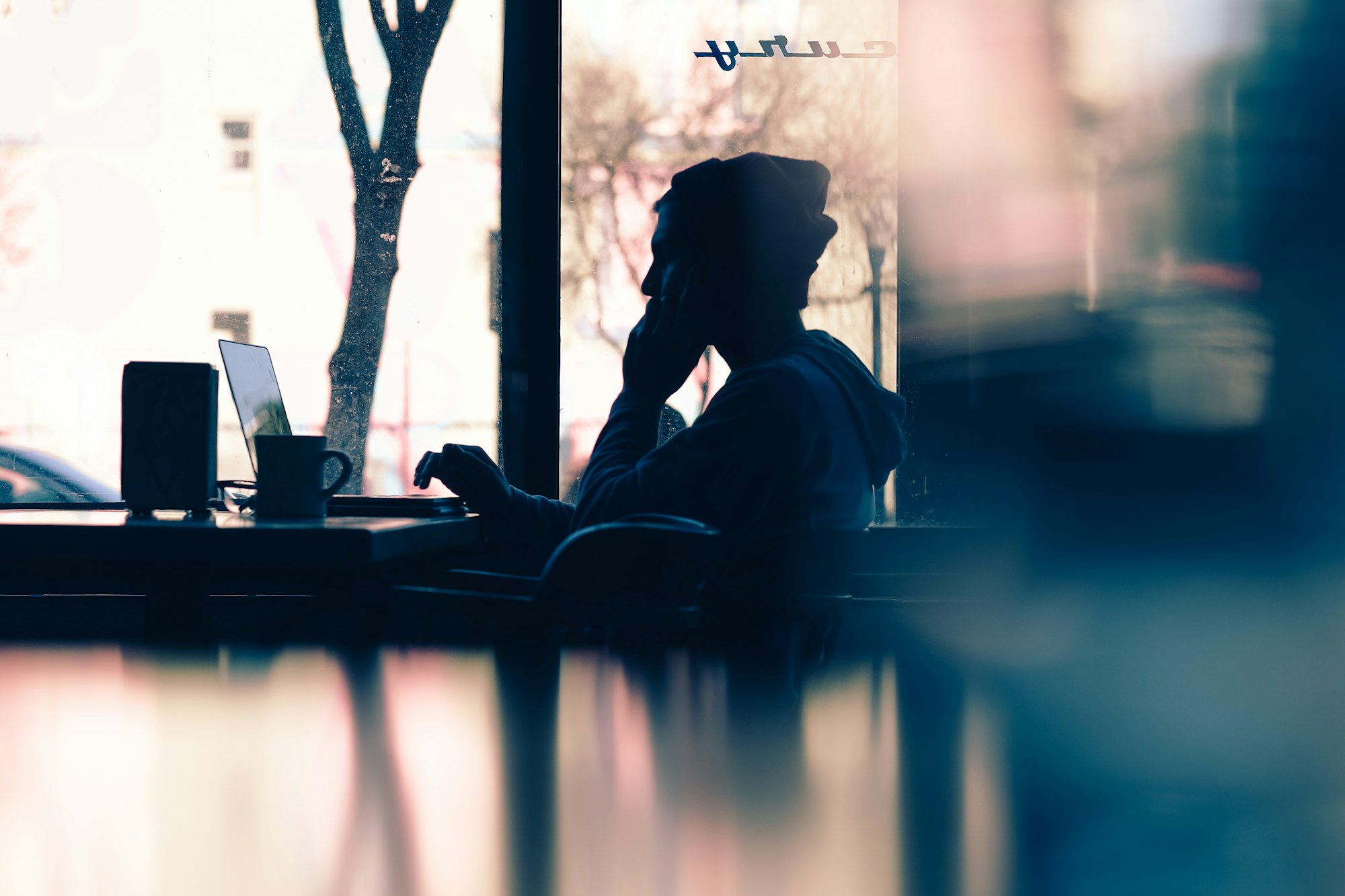 silhouette of a person sitting in front of a laptop