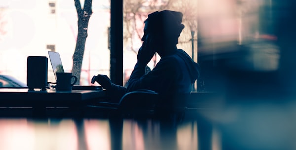 silhouette of a person sitting in front of a laptop