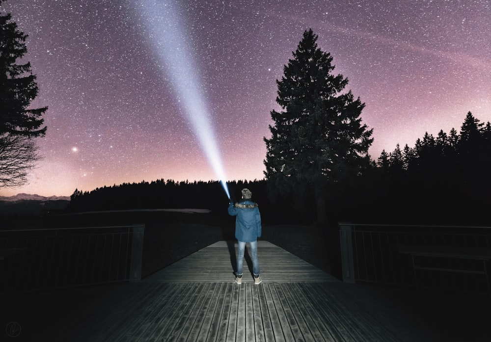 personne tenant une lampe de poche visant le ciel