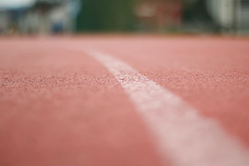 Close-up of a runner's feet pounding the track, dust kicking up with each stride.