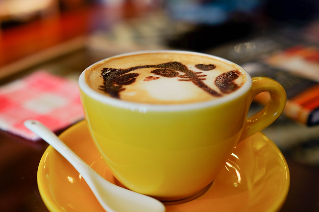 yellow ceramic teacup with cat designed coffee, Cat Cafe