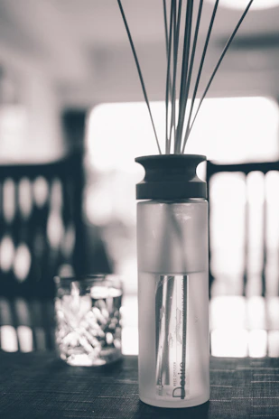 Close-up of elegant glass fragrance diffusers with delicate reeds, set against a simple, modern backdrop.